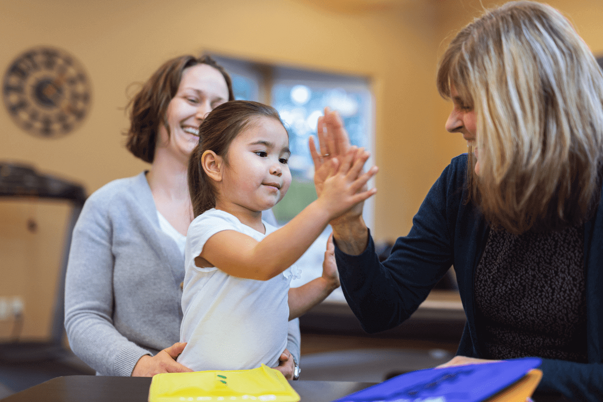 Child high-fiving adult in cheerful setting.