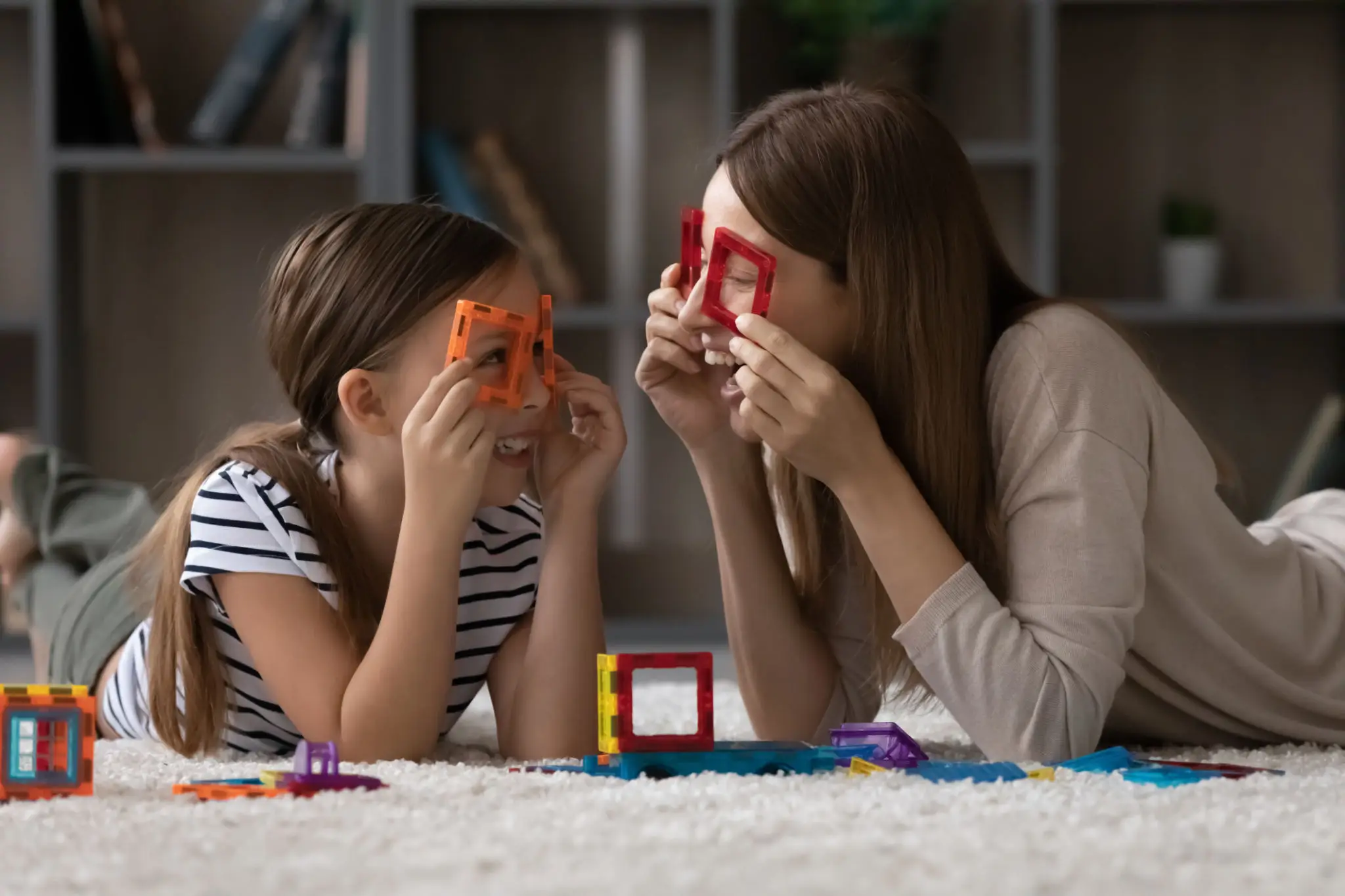 Mother and daughter playing with colorful shapes on their faces.