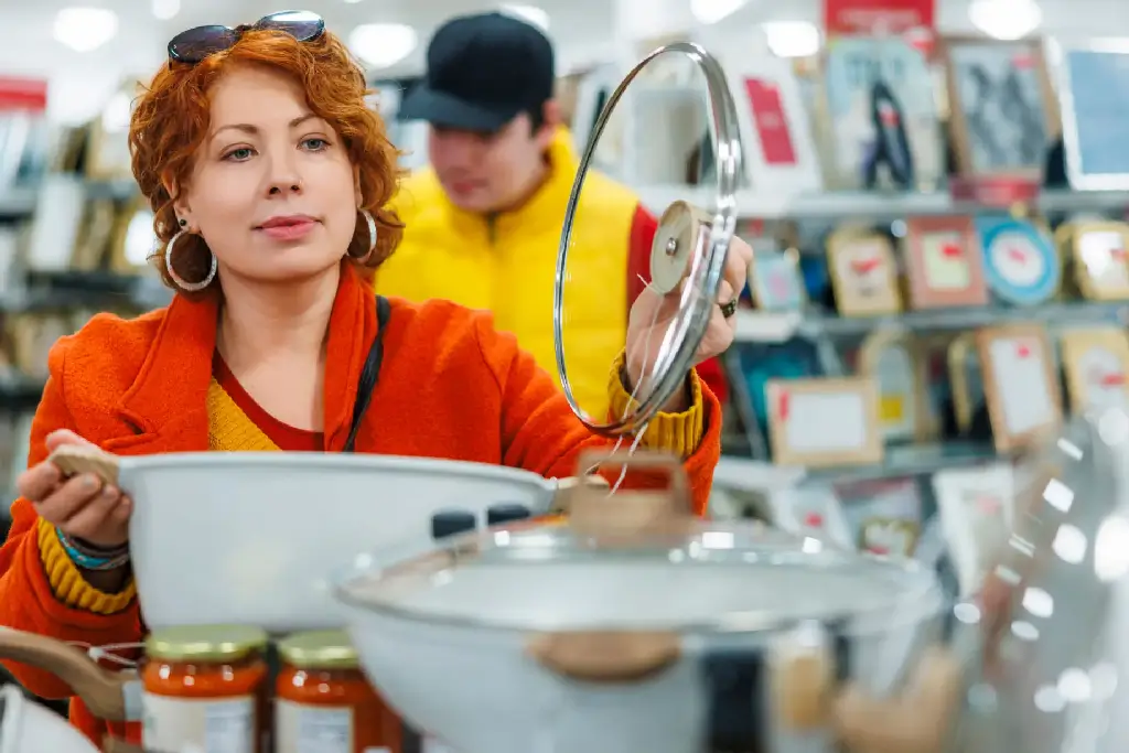 A woman shopping for utensils in a store.